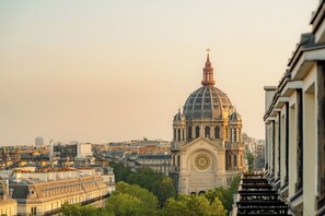 A view of a large, historic building with a prominent dome and clock tower, surrounded by dense urban architecture. - Hyatt Paris Madeleine (Paris)