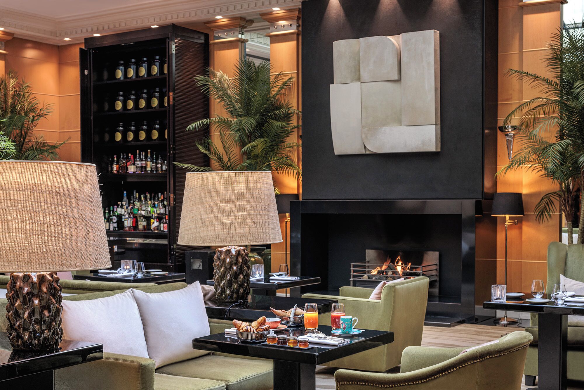 A modern lounge area with sofas, a coffee table, a fireplace, and a bar with liquor bottles.