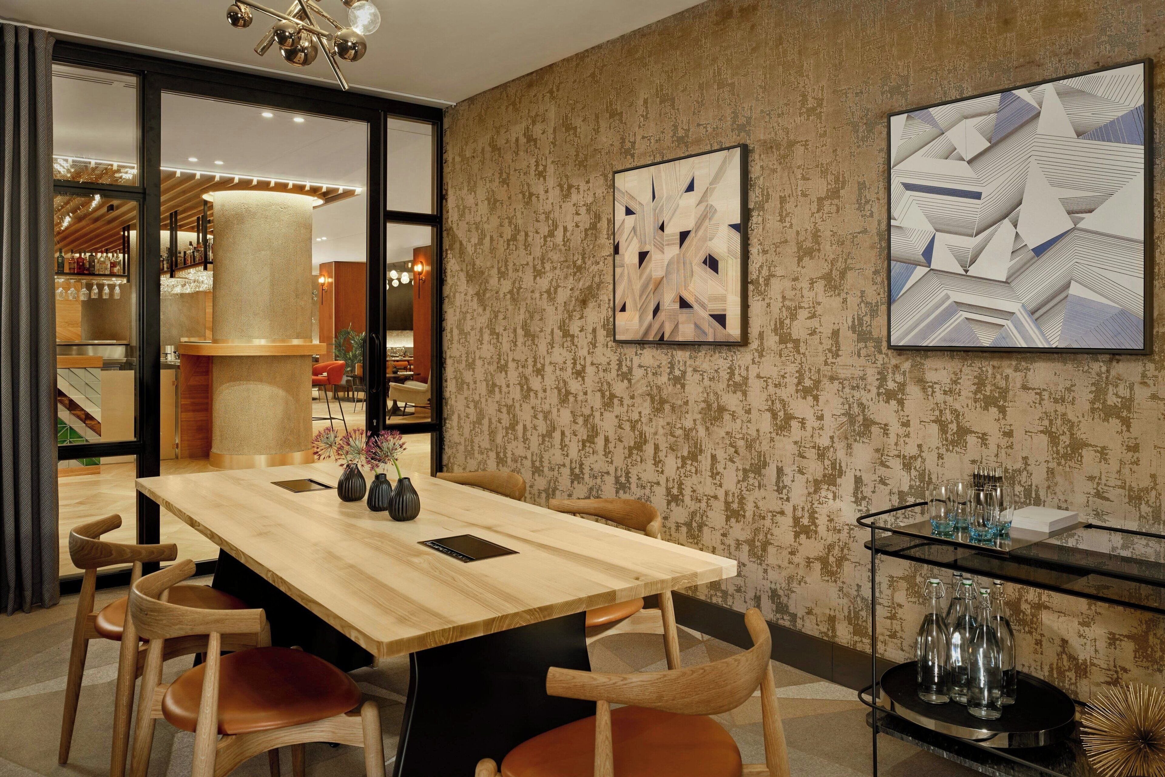 Un espace repas moderne avec une table en bois, des chaises en cuir et une table basse en verre agrémentée d’objets décoratifs.