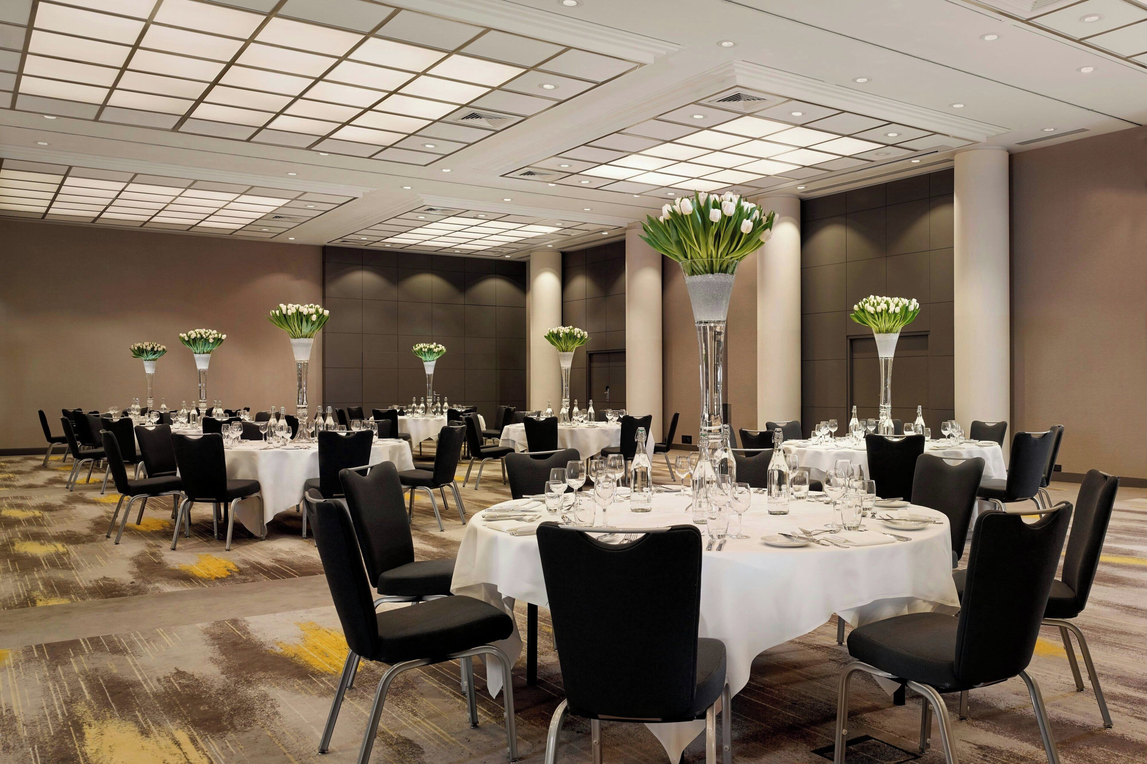 A large banquet hall with round tables set for dining, each with chairs and centerpieces.