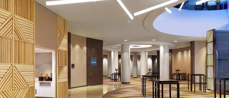 Un moderno vestíbulo de hotel con suelo curvo, paneles de madera y lámparas de diseño contemporáneo.
