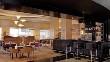 A modern bar area with a counter and bar stools, a seating area with tables and chairs, and a large window providing natural light.