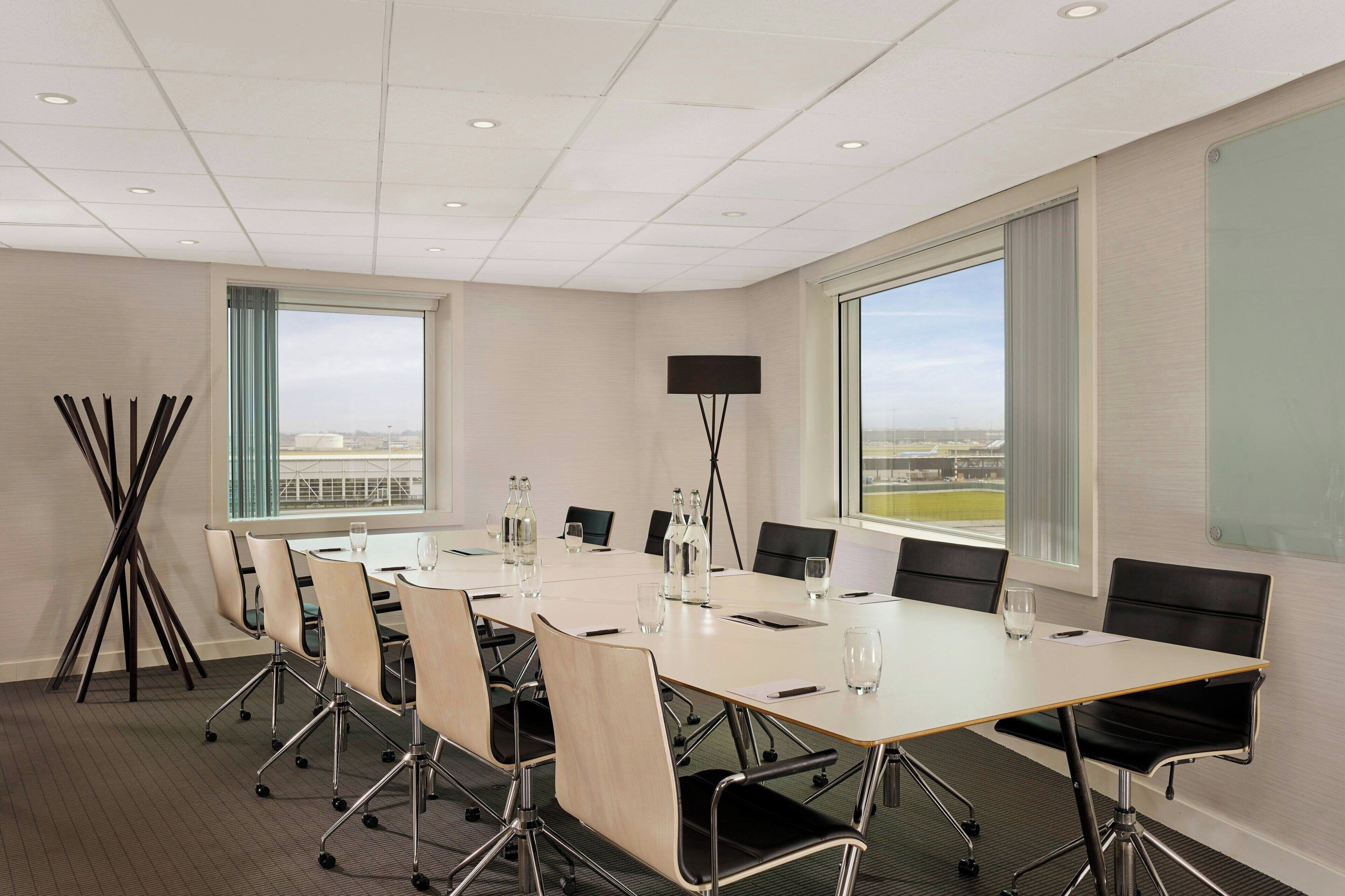A conference room with a long table, chairs, a projector, and large windows with a view.