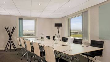 A conference room with a long table, chairs, a projector, and large windows with a view.