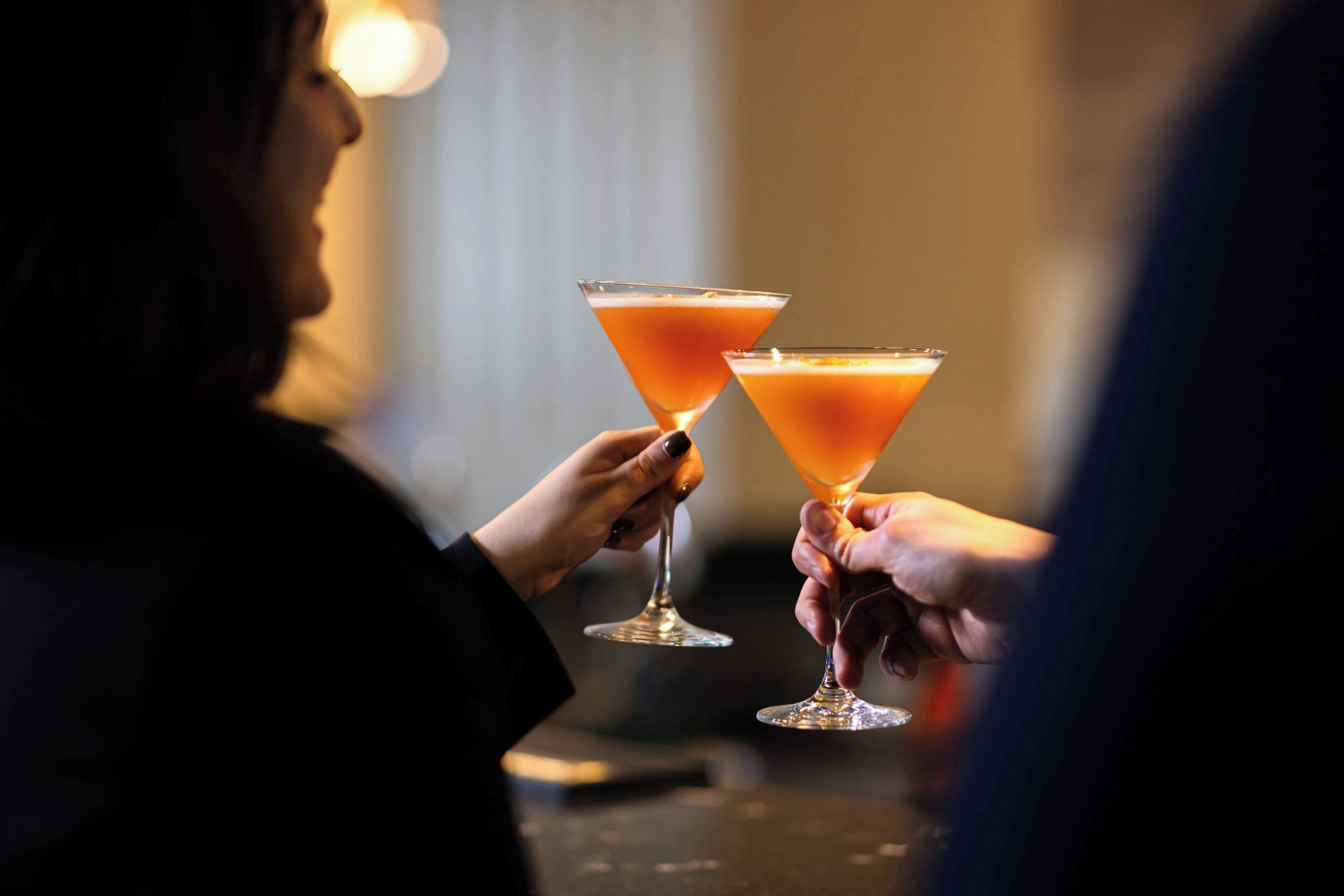 Deux personnes tenant des verres à martini remplis d’une boisson.