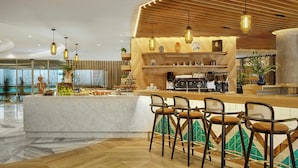 A modern bar area with a marble countertop, wooden bar stools, and pendant lighting.