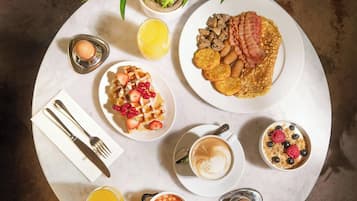 A breakfast setting with various dishes, a coffee cup, and a glass of orange juice on a round table.