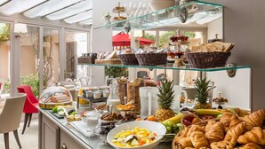 A breakfast buffet with various food items, including fruits, pastries, and beverages, displayed on glass shelves. - Hotel la Residence du Berry (Versailles)