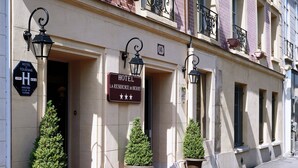 A hotel facade with a red carpet entrance, potted plants, and a sign indicating the hotel name and address. - Hotel la Residence du Berry (Versailles)