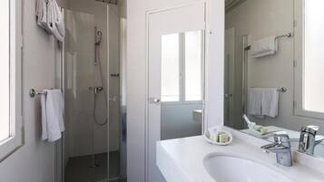 Une salle de bain moderne avec une douche à parois de verre, un lavabo blanc et un grand miroir.