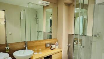 A modern bathroom with a glass-enclosed shower, a wooden vanity with a large sink, and a toilet.