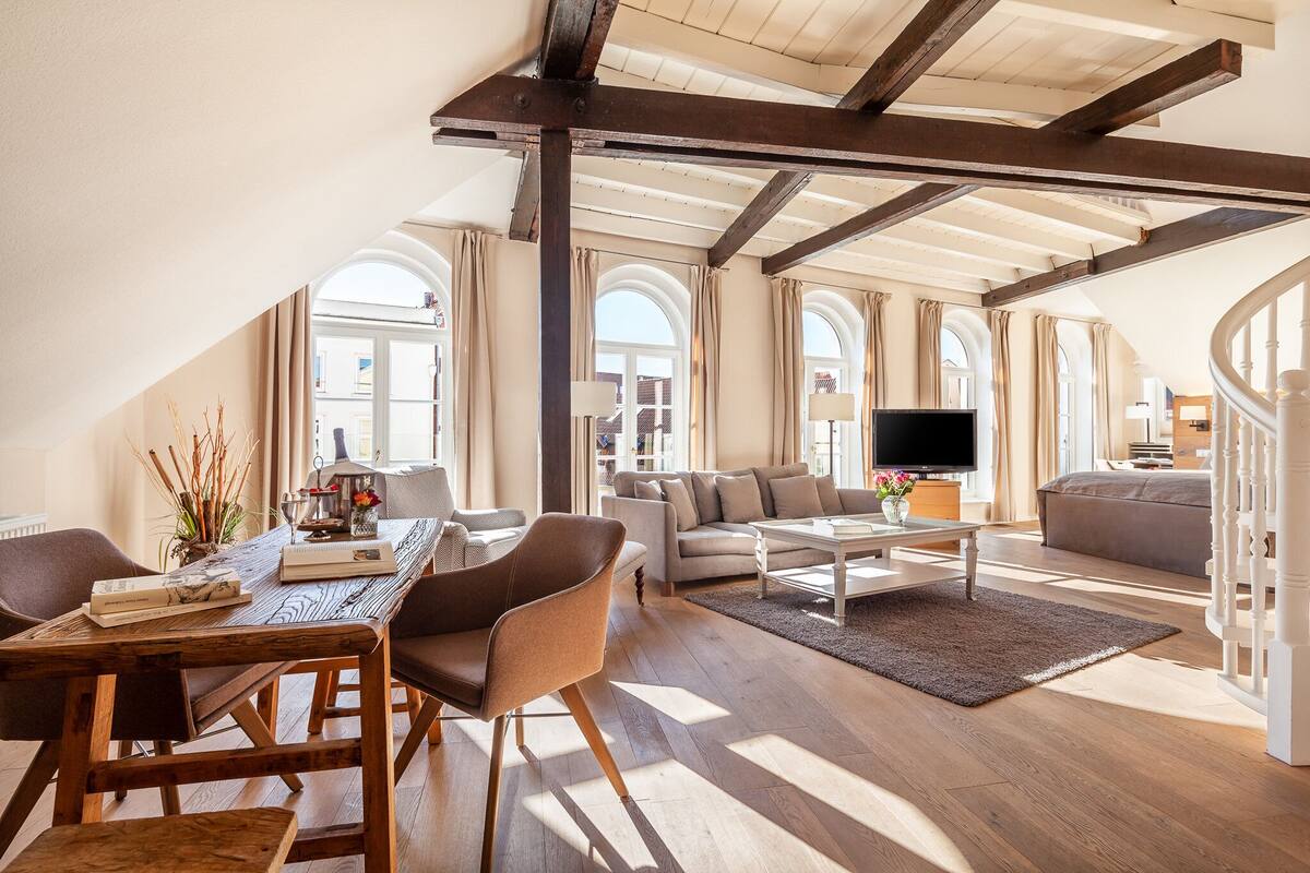 Uma sala de estar ampla com uma mesa de madeira, sofás e uma televisão.