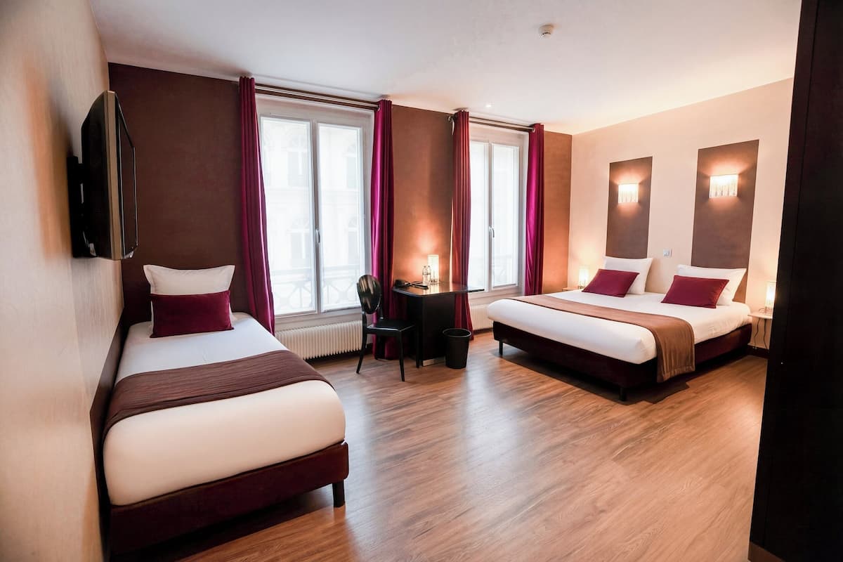 Una habitación de hotel con dos camas, un escritorio, una silla y un televisor.