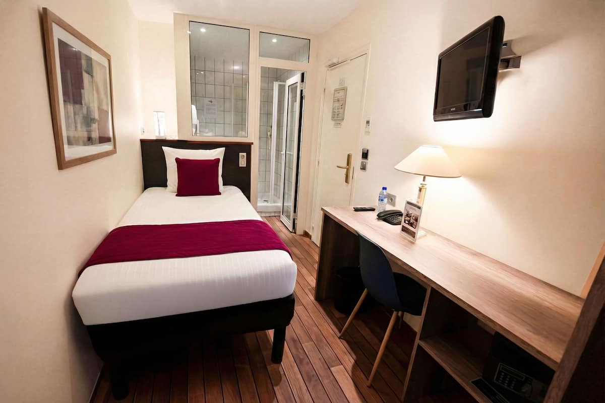 Habitación de hotel con cama, escritorio, silla, televisión y puerta que da a un baño.