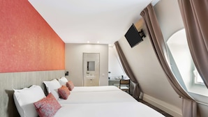 Una habitación de hotel con una cama grande, un escritorio y un ventanal con cortinas.