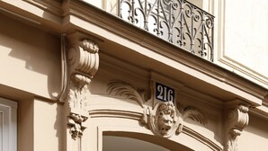Fachada de edificio con detalles arquitectónicos ornamentales, placa con un número y una puerta.