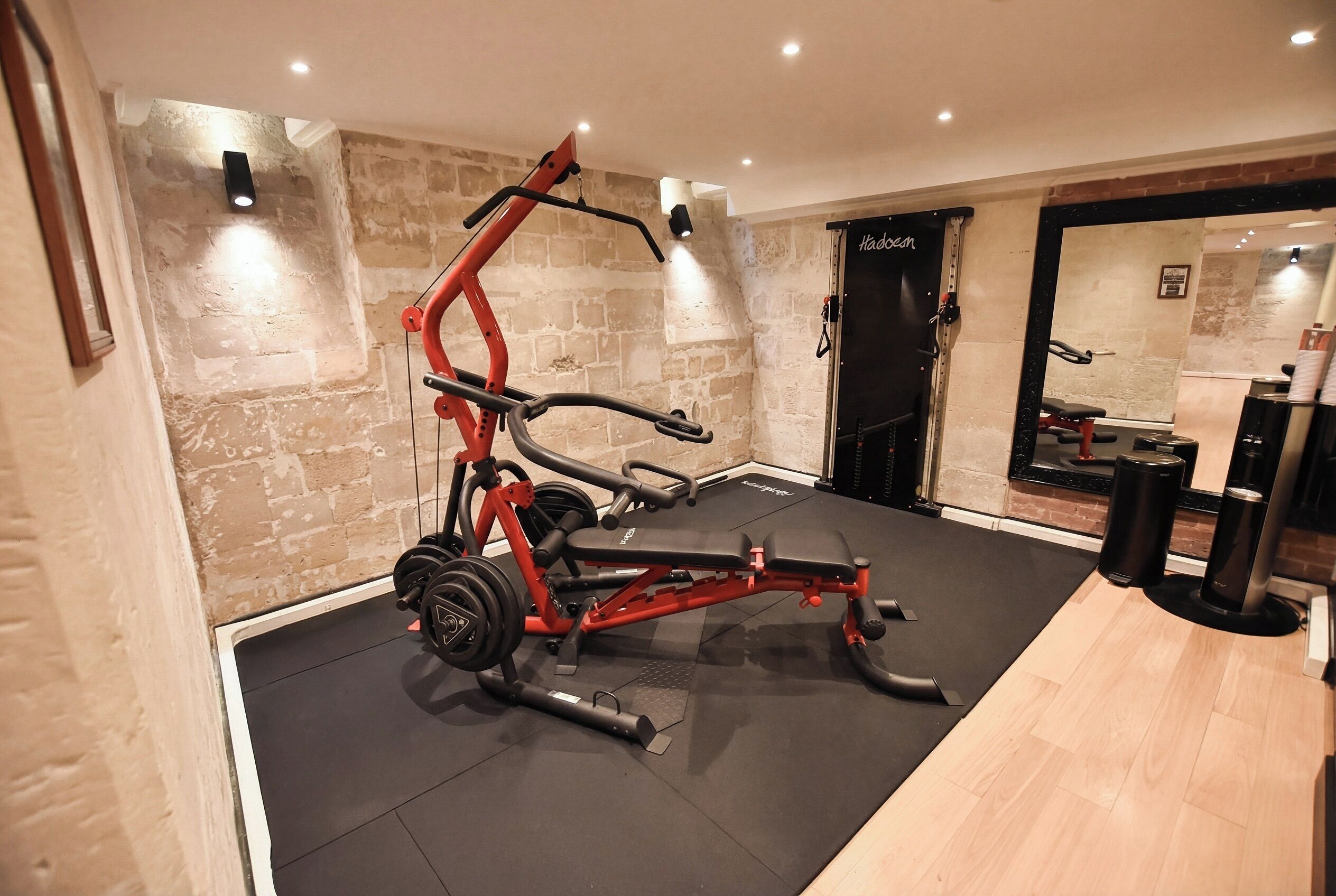 A gym with a bench press, a squat rack, and a mirror.