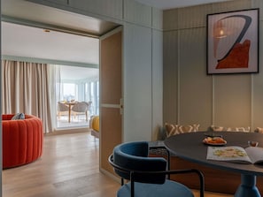 A modern room with a dining table, chairs, a red sofa, and a large window with curtains.
