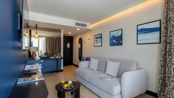 Una sala moderna con un sofá, una mesa de centro con frutas, un televisor y obras de arte en la pared.