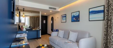 A modern living room with a sofa, a coffee table with fruits, a TV, and artwork on the wall.