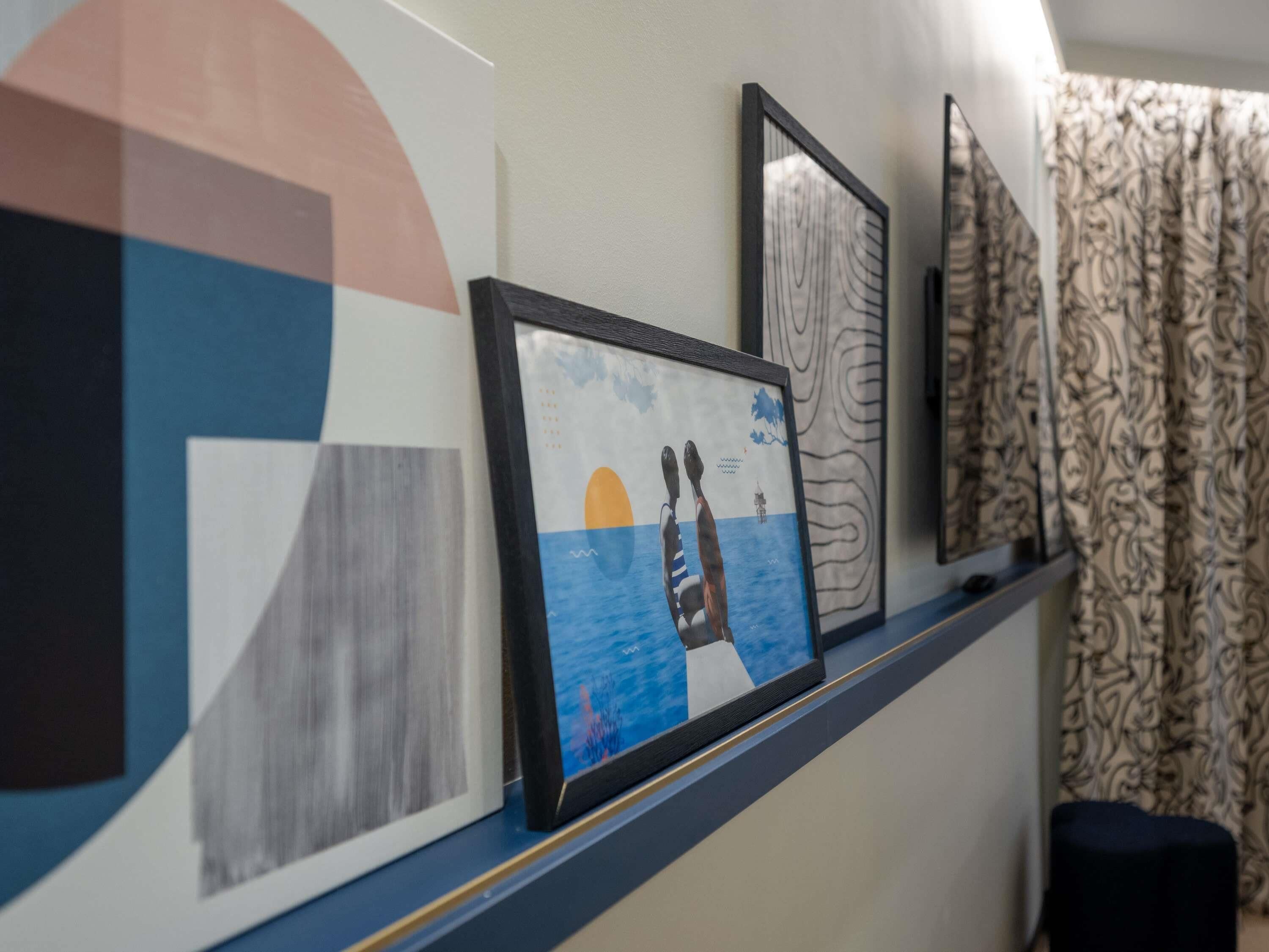 Un mur orné de tableaux encadrés, un rideau à motifs et un banc bleu.