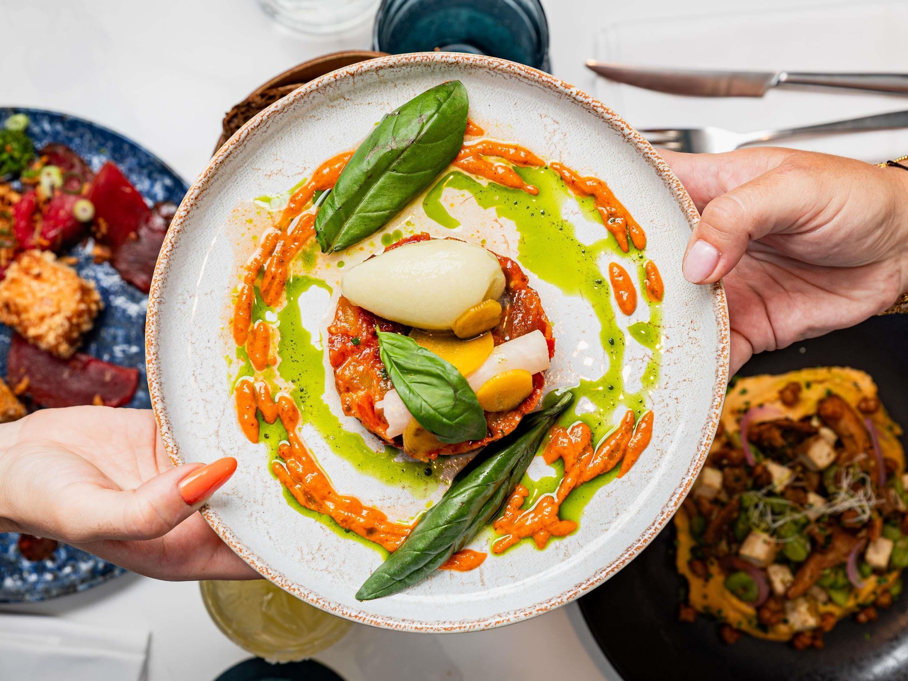 A plate of food with a variety of vegetables and a dollop of sauce.