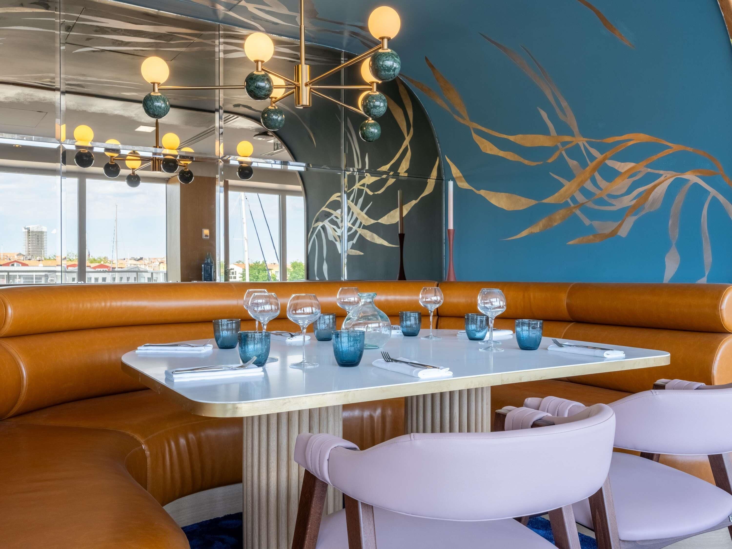 Ein Restaurant mit einer Sitzecke, einem Tisch und einer modernen Pendelleuchte.