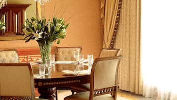 Un comedor elegante con una araña, una mesa redonda y seis sillas.