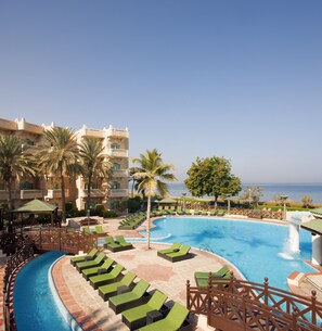 Relax by the oceanfront pool surrounded by lounge chairs and lush greenery.