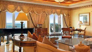 Una sala imponente con un piano de cola, muebles elegantes y grandes ventanales con vistas al mar.