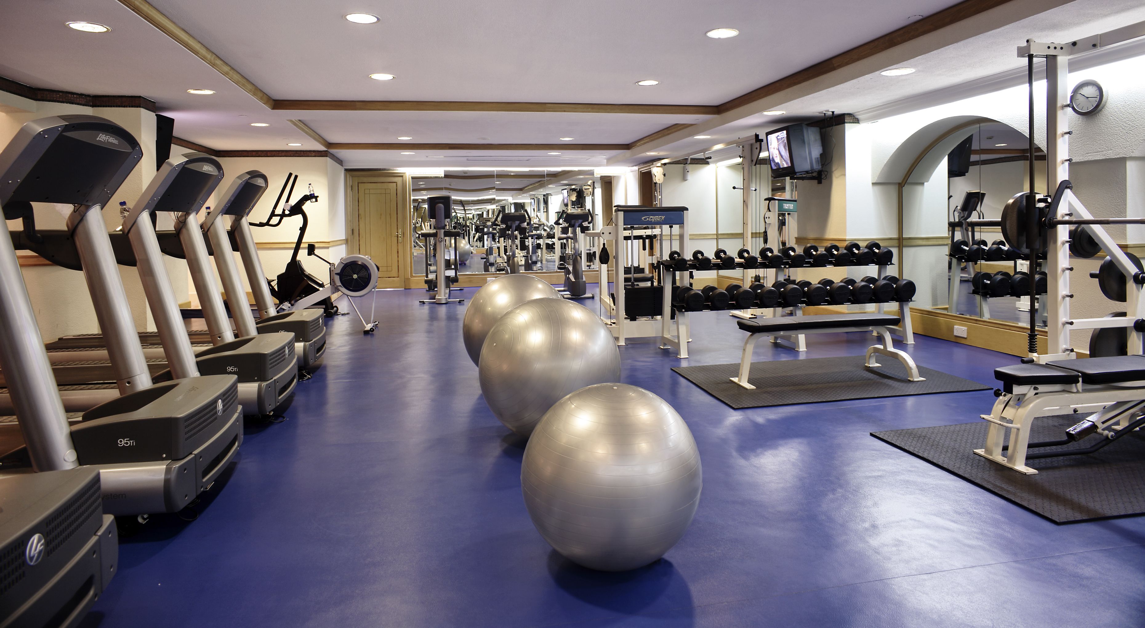 Ein Fitnessraum mit Laufbändern, Crosstrainern und Kurzhanteln.