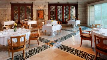 A dining area with multiple tables set for service, wooden chairs, and a patterned floor.
