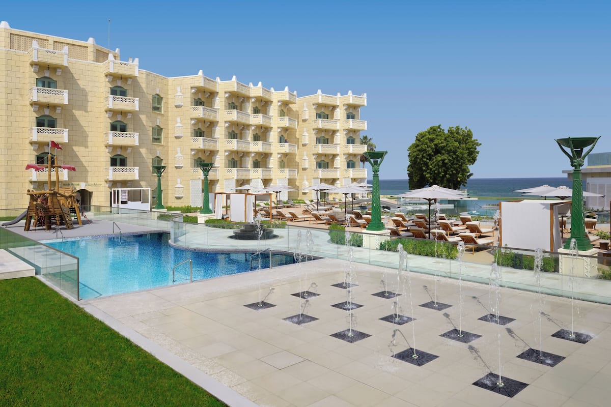 Um hotel com piscina, espreguiçadeiras e vista para o mar.