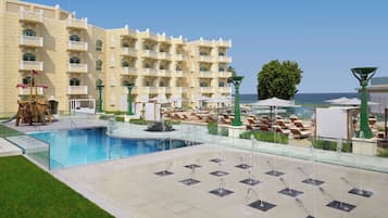 A hotel with a swimming pool, sun loungers, and a view of the sea.