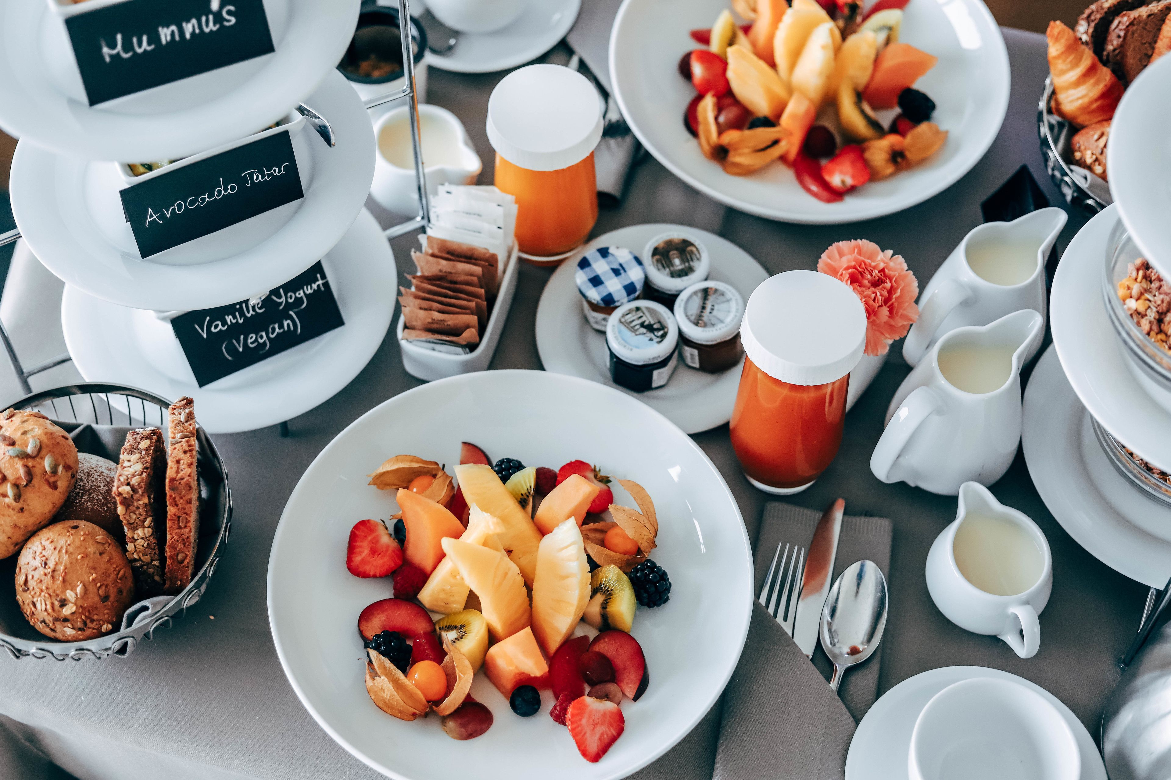 A breakfast buffet with labeled food items including hummus, avocado toast, and vegan yogurt.