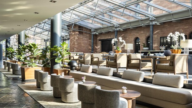 A hotel lobby with a glass ceiling, seating areas, and potted plants. - Hyatt Regency Mainz (Mainz)