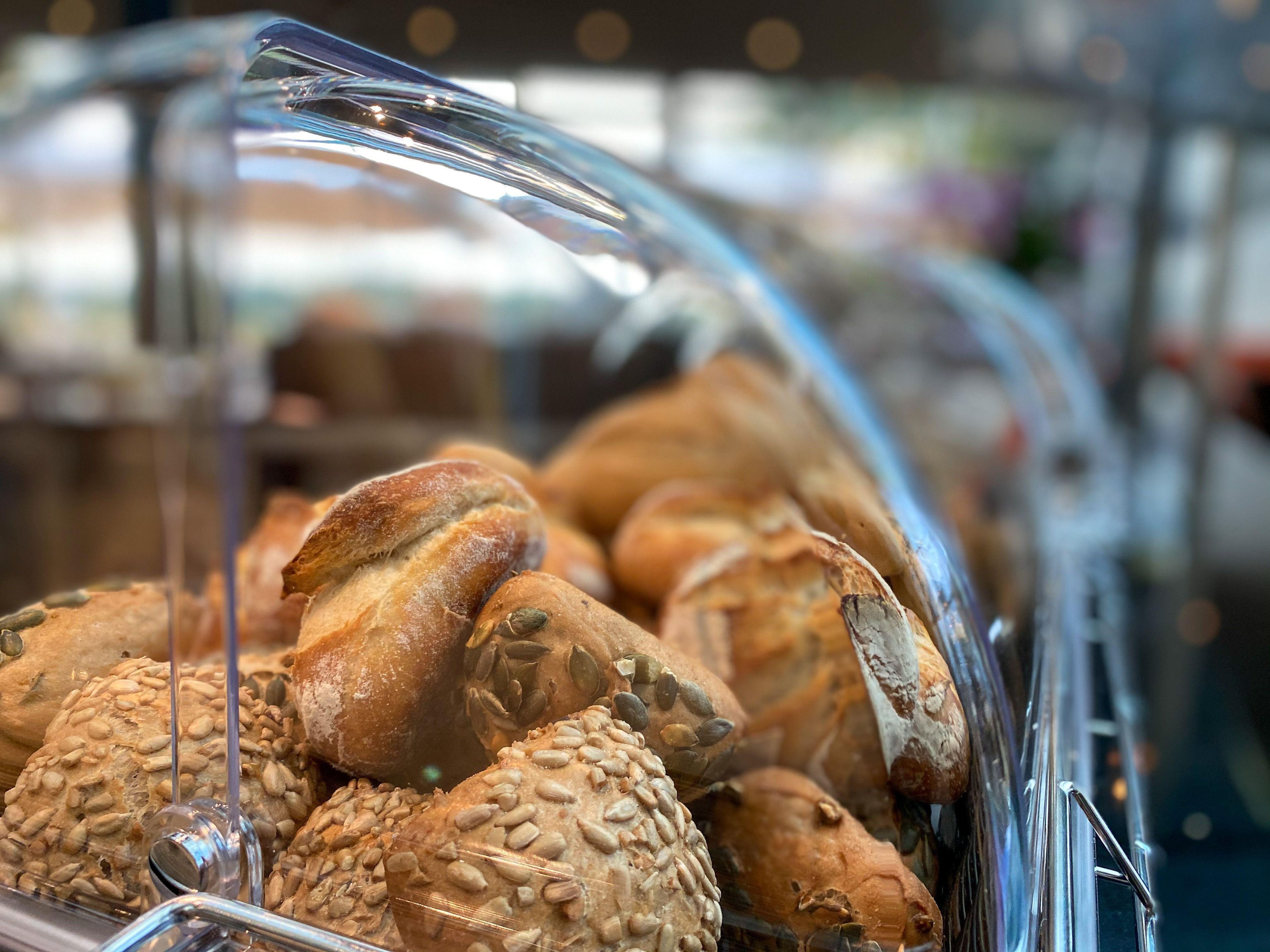 A variety of breads and pastries displayed in a glass case, likely in a bakery or deli setting.