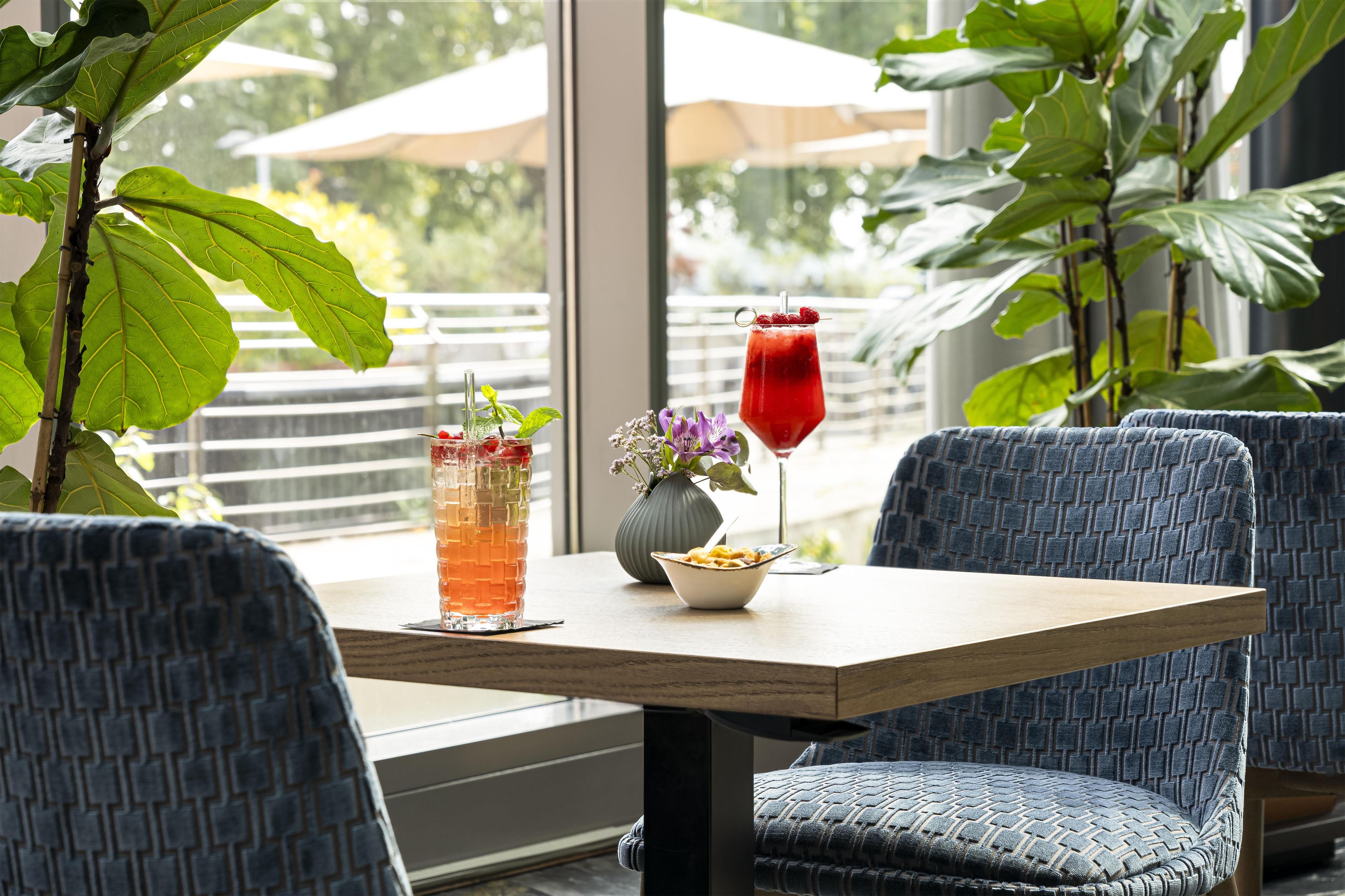 Ein Tisch mit zwei Getränken, einer Pastaschüssel und einer Vase mit Blumen.
