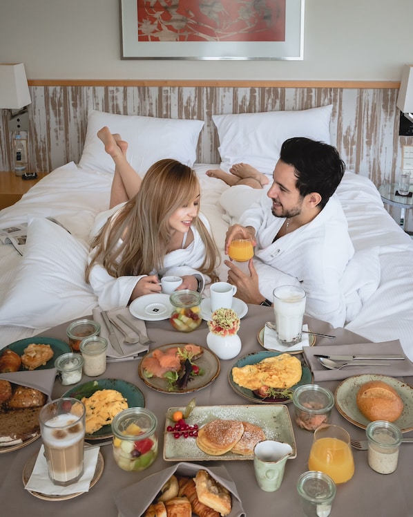 Una pareja en la cama con el desayuno servido en el suelo.