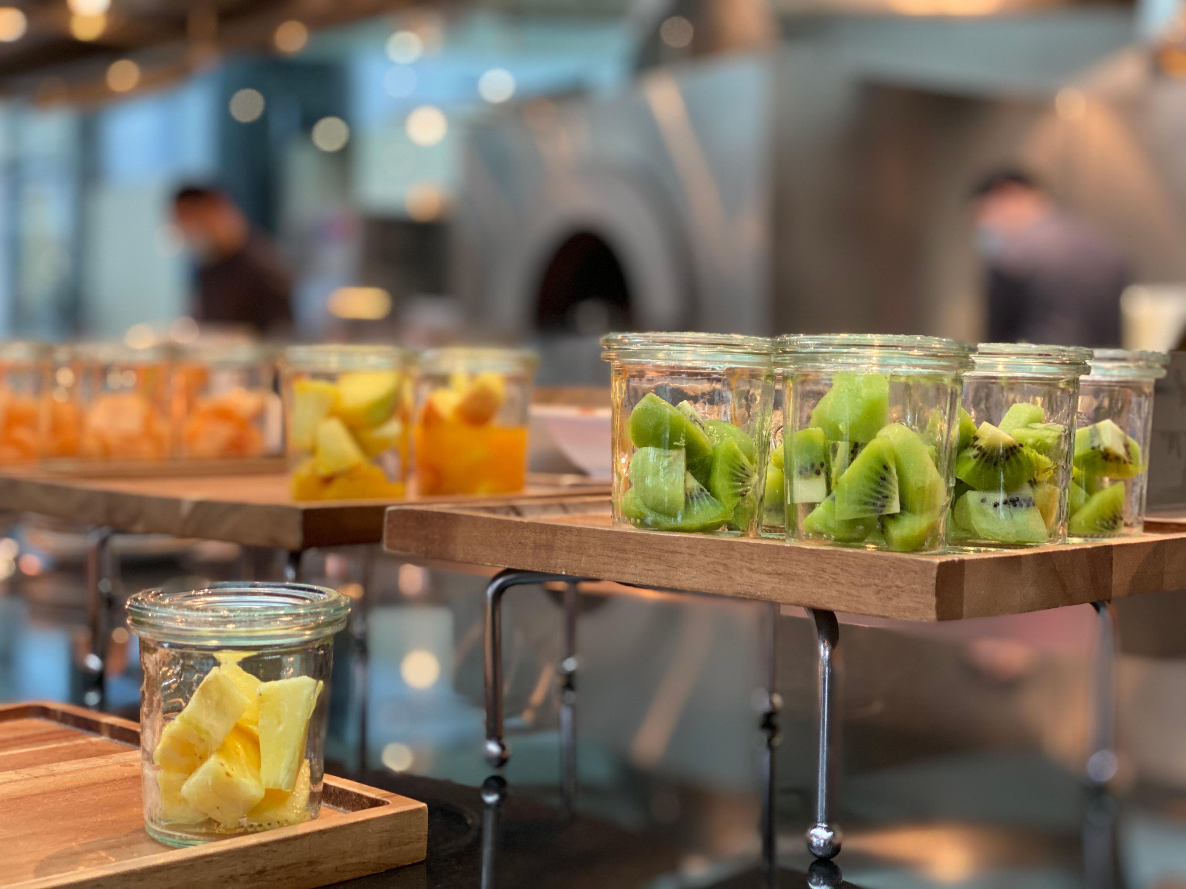 A buffet with various fruit options in glass containers on wooden serving boards.