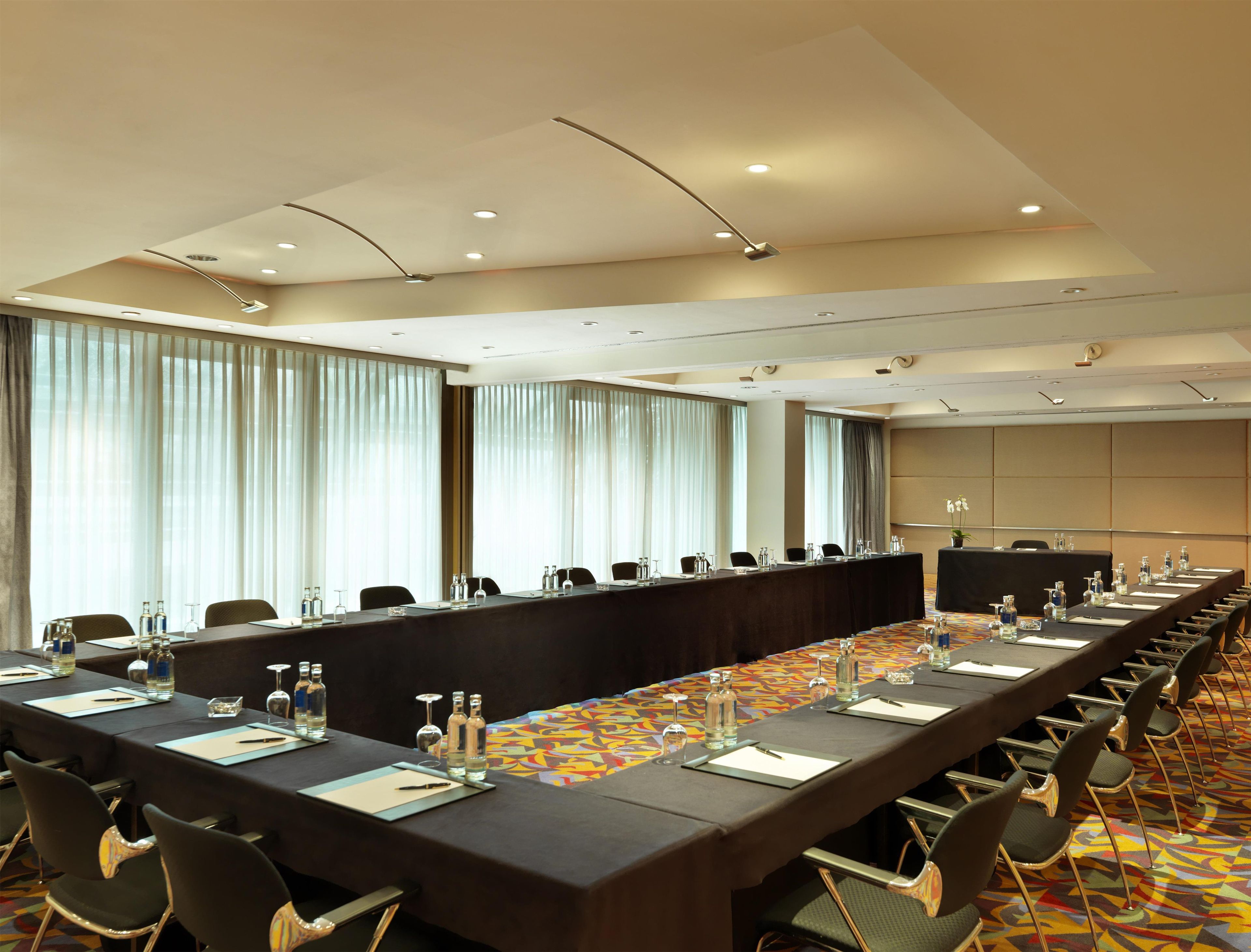 A conference room with a long table, chairs, and a patterned carpet.
