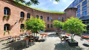 An outdoor courtyard with brick walls, multiple tables and chairs, and potted plants.