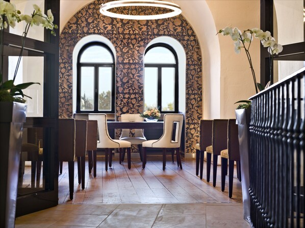 A dining area with a table and chairs, a decorative wall with floral patterns, and a ceiling light fixture. - Hyatt Regency Mainz (Mainz)