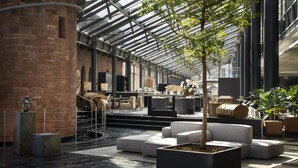A spacious indoor area with a glass ceiling, modern seating, and potted plants. - Hyatt Regency Mainz (Mainz)