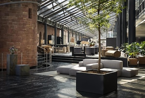 Un vaste espace intĂ©rieur dotĂ© dâun plafond en verre, de mobilier moderne et de plantes en pot.
