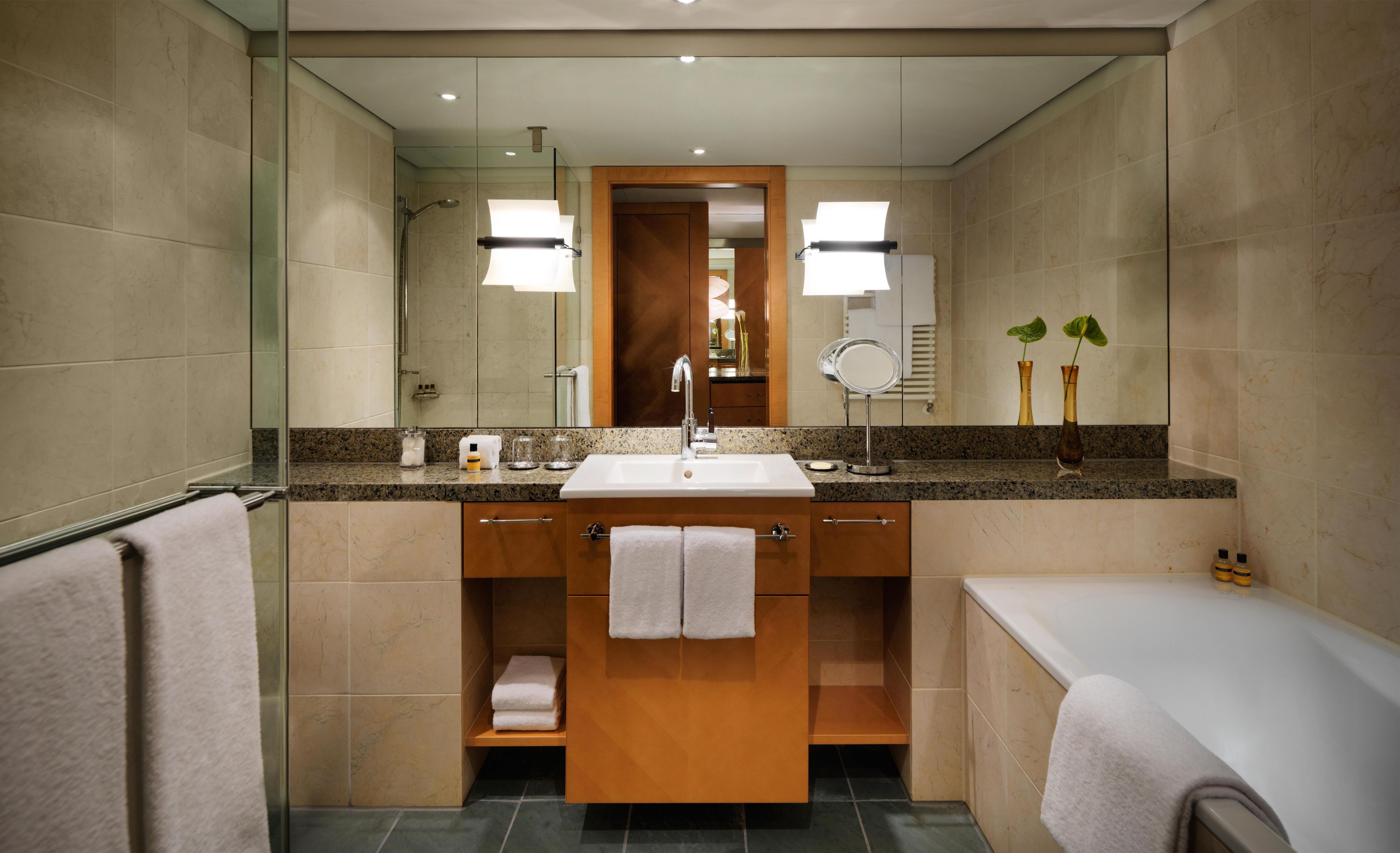 Un baño moderno con un espejo grande, un lavabo y una zona de ducha.