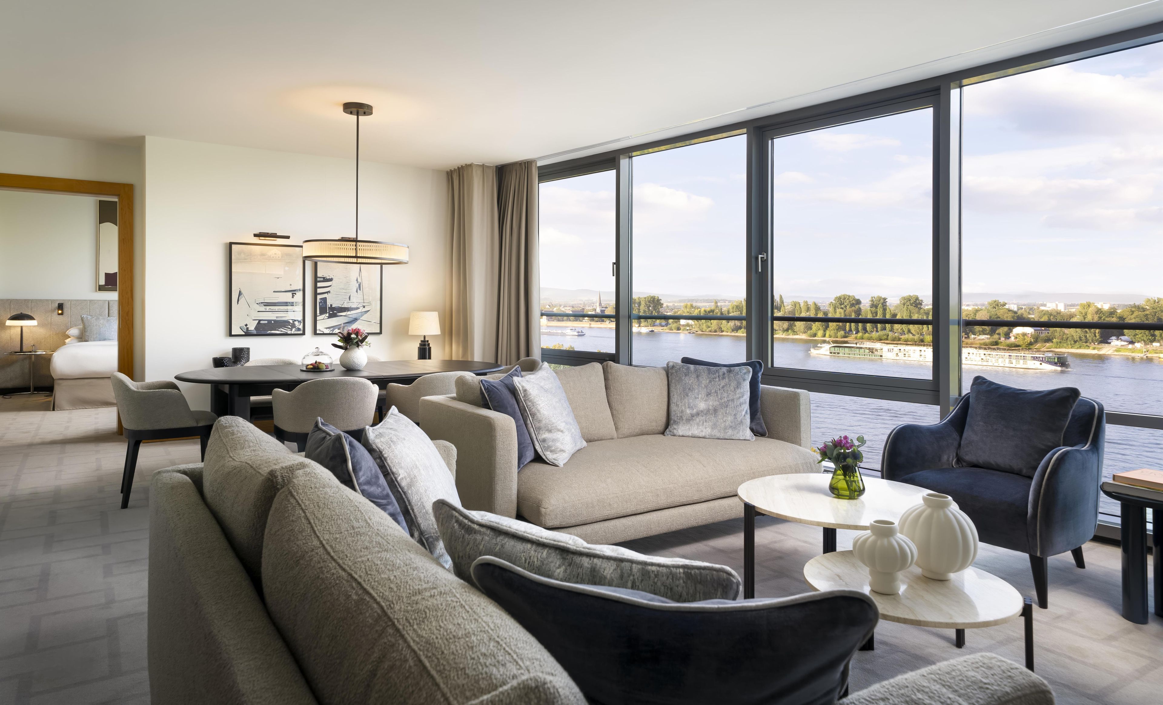 A modern hotel room with a large window offering a view of a river and cityscape.