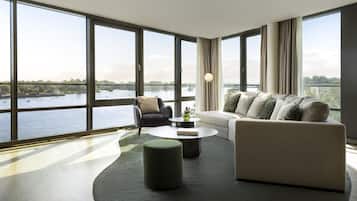 A spacious living room with large windows, a sofa, a chair, and a coffee table.