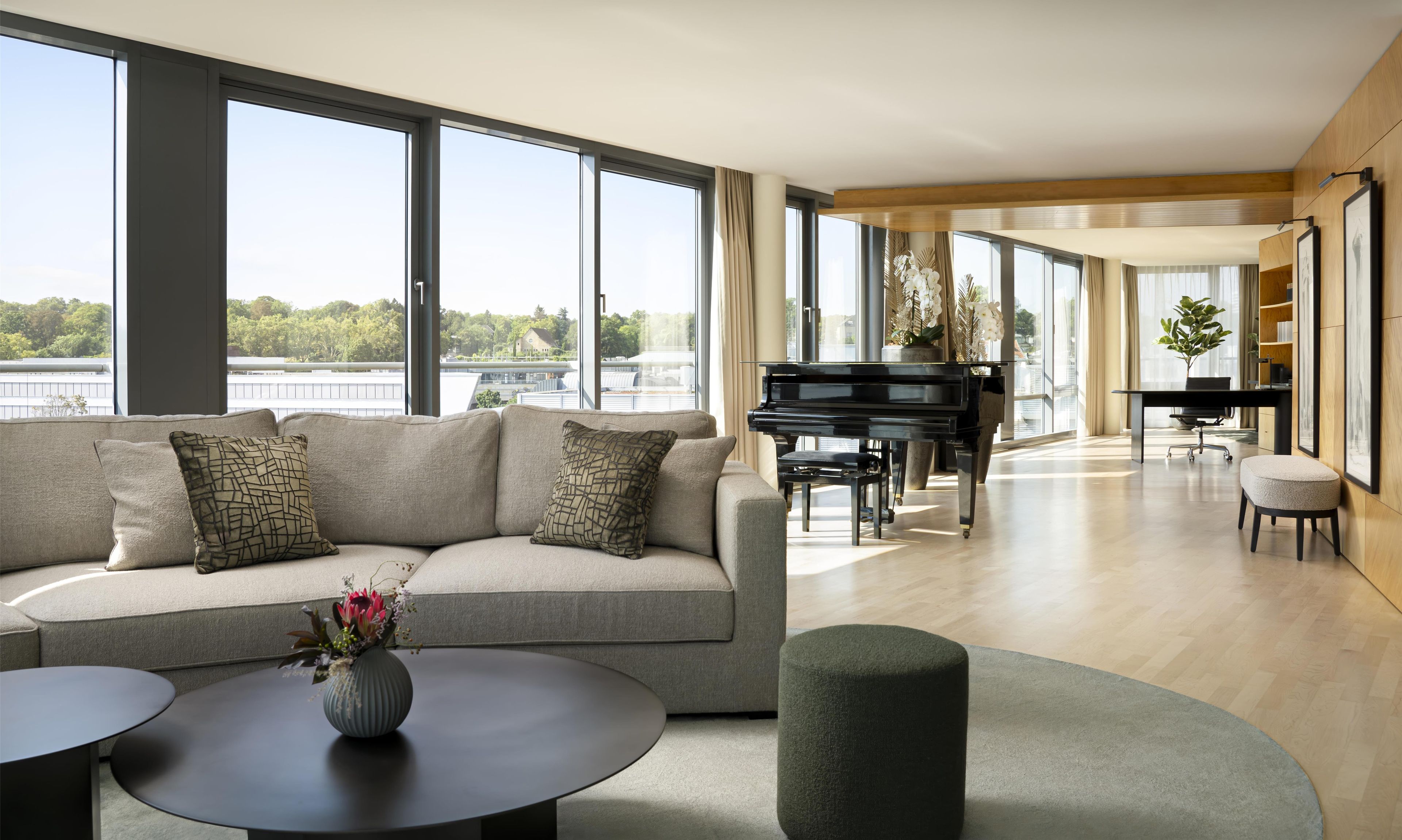 Una sala moderna con un sofá, un piano y vistas al exterior.
