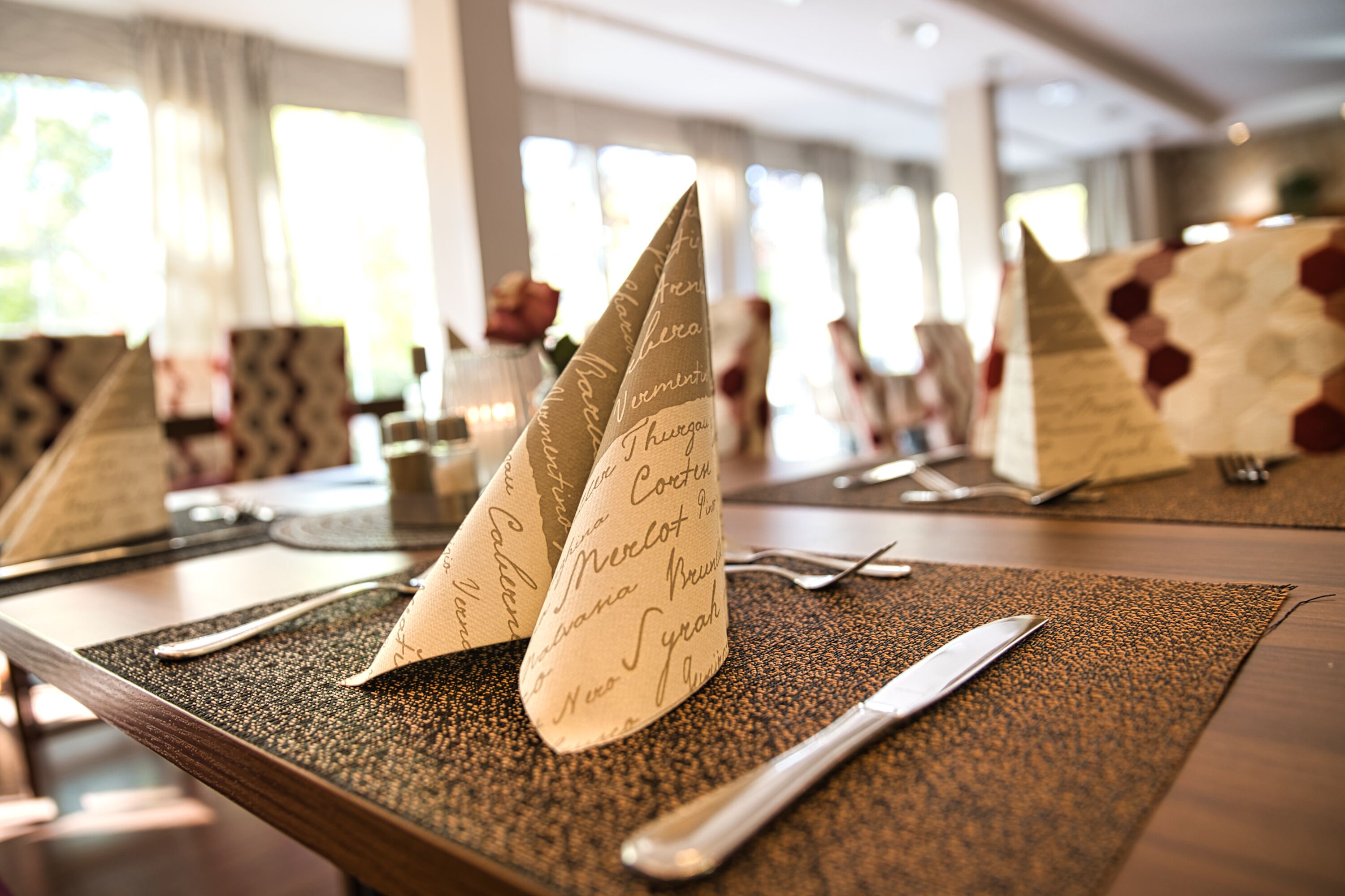 A table set with a placemat, a knife, and a folded napkin with cursive writing.